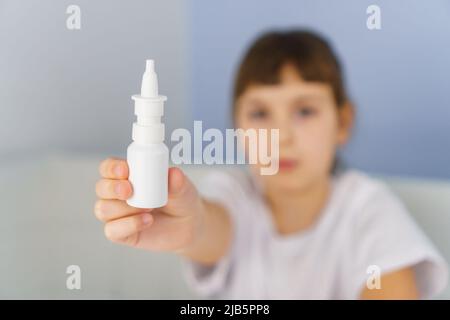 Bottiglia di spray nasale in mano di ragazza. Trattamento allergico, rinite virale e batterica e sinusite Foto Stock