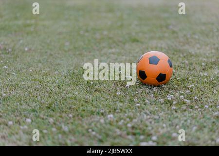 Palla di calcio sull'erba. Sfera arancione Foto Stock