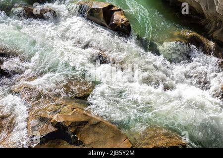 Primo piano struttura astratta sopra la vista del torrente del fiume e acqua fresca limpida che scorre attraverso le rocce di montagna in valle con schiuma e bolle su Foto Stock