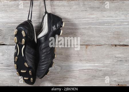 Un paio di stivali da calcio appesi su un muro di legno. La fine della carriera calcistica Foto Stock