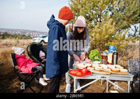 Famiglia barbecue su un ponte nella pineta. Cucina all'aperto. Foto Stock