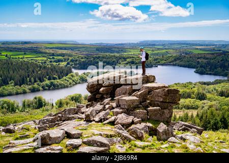 Un camminatore si erge su uno affioramento di granito sulla Lower Leather Tor, che si affaccia sul Burrator Reservoir, Dartmoor National Park, Devon, Regno Unito. Foto Stock