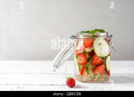 Acqua infusa con fragola e meloncella che è ibrido di cetriolo e melone, timo, menta. Spazio di copia. Foto Stock