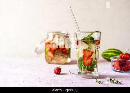 Acqua infusa con fragola e meloncella che è ibrido di cetriolo e melone, timo, menta. Spazio di copia. Foto Stock