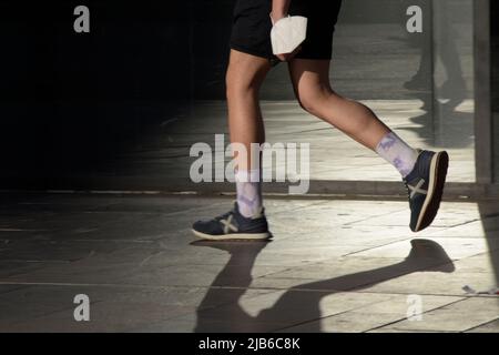 Particolare delle gambe di un uomo con scarpe sportive che cammina per la strada. Foto Stock