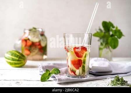 Acqua infusa con fragola e meloncella che è ibrido di cetriolo e melone, timo, menta. Foto Stock