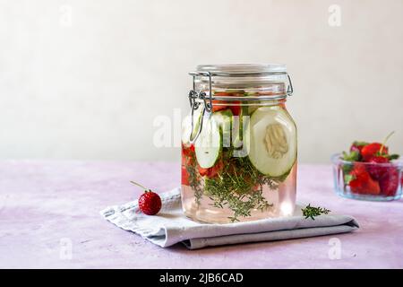 Acqua infusa con fragola e meloncella che è ibrido di cetriolo e melone, timo, menta. Spazio di copia. Foto Stock