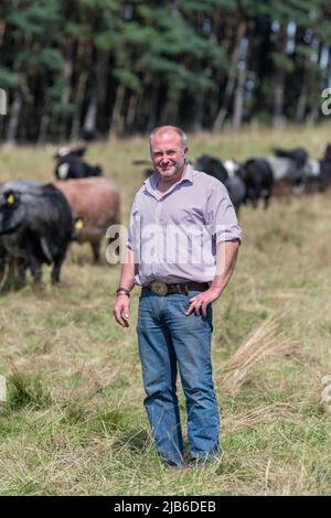 Coltivatore con bestiame nativo, utilizzato come parte di agricoltura rigenerativa nella sua fattoria per contribuire a migliorare la qualità del suolo, Co. Durham UK. Foto Stock