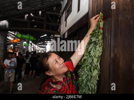 (220603) -- CHONGQING, 3 giugno 2022 (Xinhua) -- un residente locale appende un fascio di mugwort sulla porta nel distretto di Yongchuan nel comune di Chongqing della Cina sud-occidentale, 3 giugno 2022, il giorno del festival tradizionale della barca del drago della Cina. (Xinhua/Wang Quanchao) Foto Stock