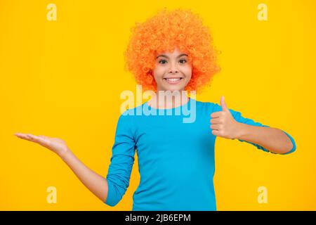 Bella ragazza adolescente in parrucca isolato sul giallo. Divertente clown wig. Buon ritratto adolescente. Ragazza sorridente. Foto Stock