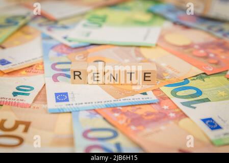 La parola rente - in tedesco per rendita - sulle banconote banconote banconote Euro scritte con cubo di legno Foto Stock