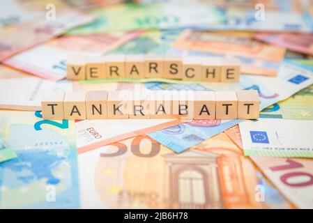 La parola Tankrabatt - in tedesco per sconto carburante - e verarsche - in tedesco per imbrogliare - sullo sfondo delle banconote banconote banconote banconote Euro banconote scritte in legno Foto Stock