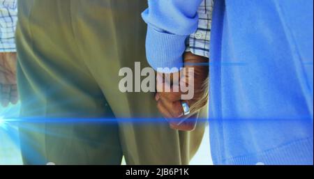 Immagine della luce che si sposta sulla parte centrale della coppia anziana che cammina tenendo le mani Foto Stock