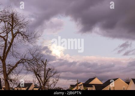 Un cielo oscuro e cupo prima di una tempesta di pioggia con il sole che sbuca su un nuovo quartiere costuzioni Foto Stock