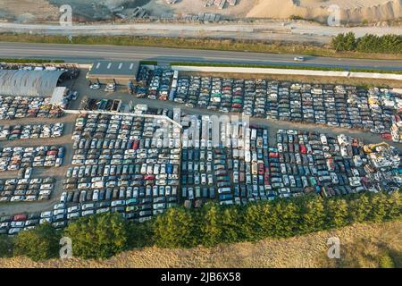 Vista aerea del grande parcheggio di junkyard con file di auto scartate rotte. Riciclaggio dei vecchi veicoli. Foto Stock