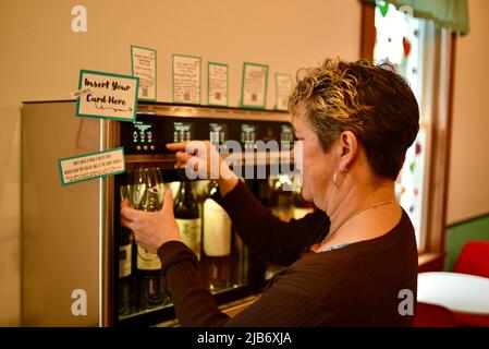 Cliente donna che utilizza il sistema di erogazione automatica del vino, Wine-e-Motion, utilizzando la carta Wine-o-Matic presso Vintage, Elkhart Lake, Wisconsin, USA Foto Stock