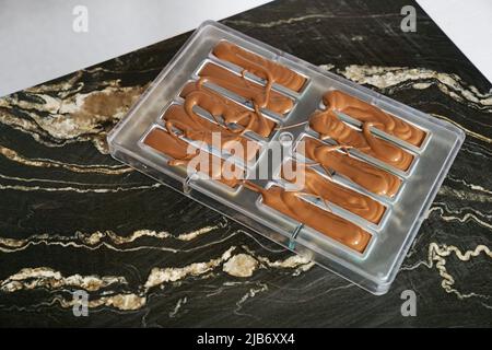 Cioccolato versato in stampo di plastica. Concetto per preparare dessert fatti in casa al cioccolato Foto Stock