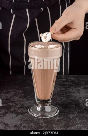 bevanda al cacao decorata con divertenti biscotti su sfondo scuro in una caffetteria Foto Stock