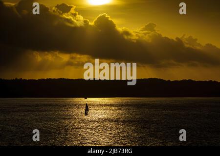 Tramonto isola sylt Mar Baltico Germania, vista romantica, barca a vela all'orizzonte molto vicino al sole Foto Stock