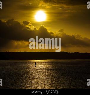 Tramonto isola sylt Mar Baltico Germania, vista romantica, barca a vela all'orizzonte molto vicino al sole Foto Stock