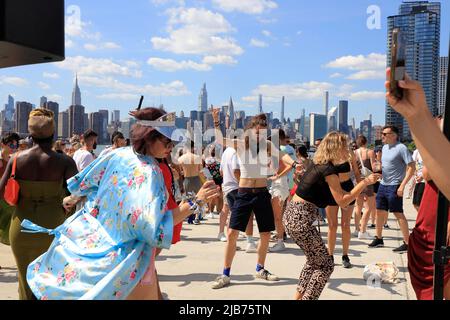 Persone che ballano al Hot Honey Sunday, festa all'aperto di ballo al Greenpoint Terminal Market con East River e lo skyline di Manhattan sullo sfondo.Greenpoint.Brooklyn.New York City.USA Foto Stock