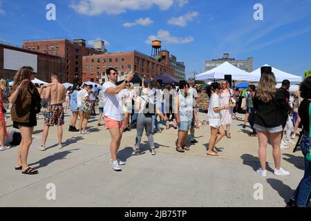 Le persone che ballano all'Hot Honey Sundays ballano all'aperto nel Greenpoint Terminal Market con East River e Manhattan skyline in background.Cree Foto Stock