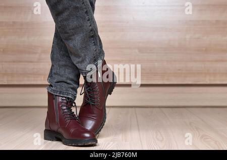 Primo piano di gambe donna in stivali di pelle rossa e jeans neri Foto Stock