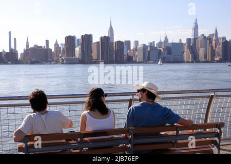 I visitatori si rilassano sul lungomare del WNYC Transmitter Park con l'East River e lo skyline di Manhattan sullo sfondo.Greenpoint.Brooklyn.New York City. Foto Stock