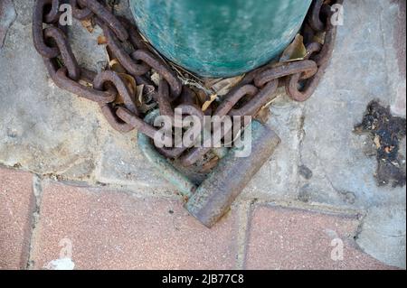 Primo piano porta in legno sulla strada privata, chiusa con una catena e un lucchetto arrugginito. Primo piano Foto Stock