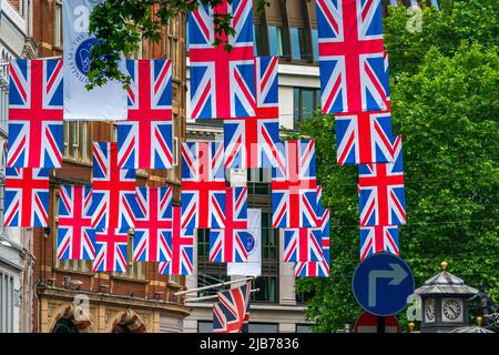 LONDRA, UK - 03 GIUGNO 2022: File di bandiere dell'Unione appendono sopra una strada nel centro di Londra per celebrare le celebrazioni del Giubileo del platino della regina. Foto Stock