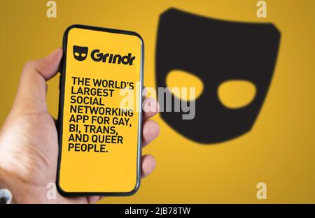 San Francisco, CA, USA, maggio 2022: Tenere a mano un telefono con l'applicazione mobile Grindr sullo schermo. Sullo sfondo il logo Grindr si offuscava. Grindr è datin Foto Stock