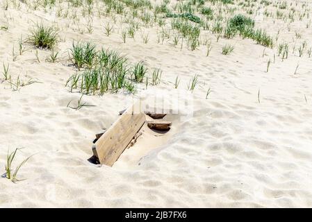 Panca di parco sepolto in sabbia ad una spiaggia di Amagansett Foto Stock