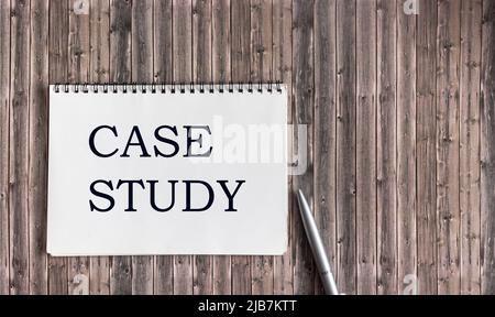 Blocco note con l'iscrizione CASE STUDY su uno sfondo di legno vicino alla penna. Concetto di banner ecologico Foto Stock