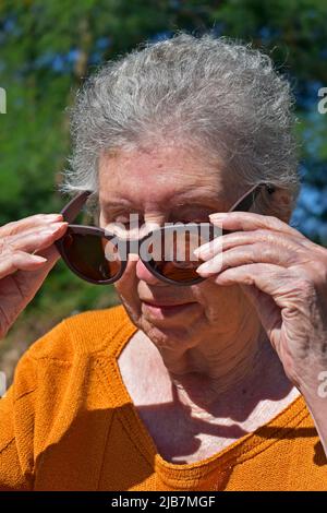 Donna anziana che indossa occhiali da sole Foto Stock