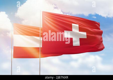 Cielo azzurro soleggiato e bandiere di svizzera e austria Foto Stock