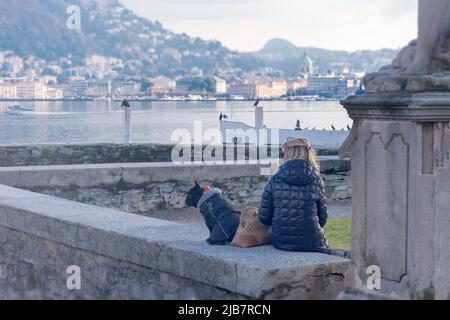 Como, Italia, novembre 2021. Una ragazza e un cane guardano il lago di Como dal giardino di Villa Olmo in provincia di Como, Italia, Lombardia sulle rive di Foto Stock