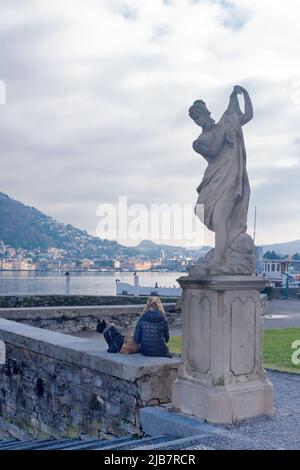 Como, Italia, novembre 2021. Una ragazza e un cane guardano il lago di Como dal giardino di Villa Olmo in provincia di Como, Italia, Lombardia sulle rive di Foto Stock