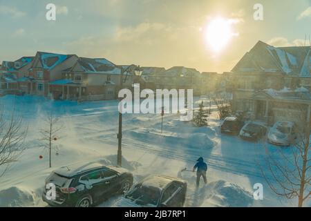 Dopo una tempesta di neve notturna, un uomo con una pala pulisce l'uscita dal cantiere dalla neve Foto Stock