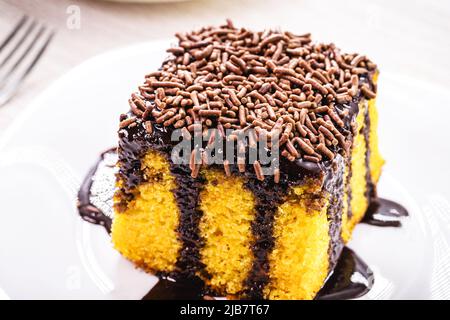 Torta di carota con spolverate di cioccolato, glassa cremosa che gocciola sulla torta, dolce tipico brasiliano alle feste di giugno Foto Stock