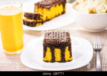 torta di carote con spolverini di cioccolato, glassa cremosa che gocciola la torta, servita con succo d'arancia Foto Stock