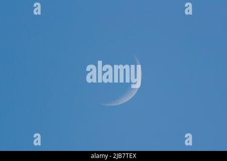 La luna crescente di ceretta contro il cielo blu, superficie visibile al 16% Foto Stock