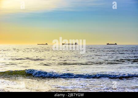 Navi ormeggiate all'orizzonte in attesa di andare al porto durante l'alba sulla spiaggia di Ipanema a Rio de Janeiro Foto Stock