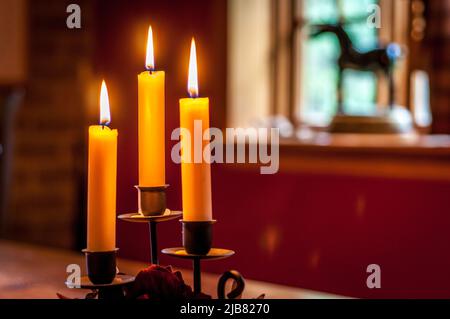 candele incandescenti su un tavolo davanti a una finestra Foto Stock