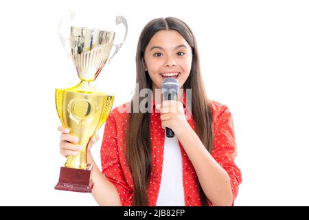 Ragazza con microfono a coppa di vincita discorso. Teen che tiene un trofeo. Bambino vincitore del capretto ha vinto la concorrenza, celebrando il successo e la vittoria. Ritratto di felice Foto Stock