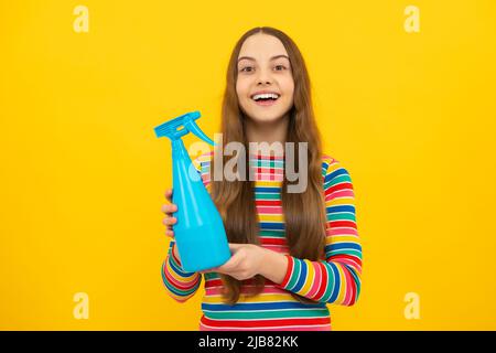 Giovane ragazza che tiene il flacone di detergente. Happy Kid tenere disinfettante spray prodotto in bottiglia per spazio copia sfondo giallo, disinfezione. Foto Stock