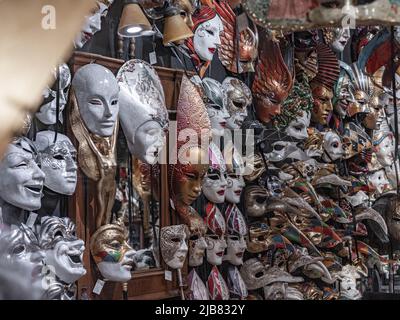 Venezia, Italia - 18.02.2022: Primo piano delle decine di maschere tradizionali veneziane, colorate, appesi al muro in un negozio di maschere a Venezia Foto Stock