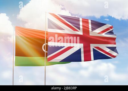 Cielo azzurro soleggiato e bandiere del regno unito e della libia Foto Stock