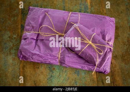 regalo confezionato in regalo, avvolto in tessuto viola e con arco a corda Foto Stock