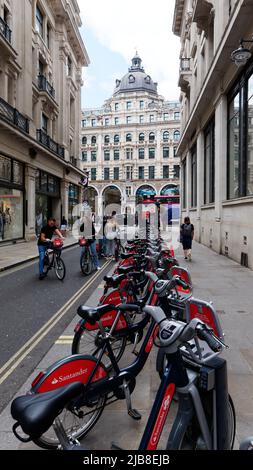 Londra, Greater London, Inghilterra, maggio 28 2022: Santander Hire Cycles aka Borris Bikes su Little Argyll Street con edifici su Regent Street alle spalle. Foto Stock