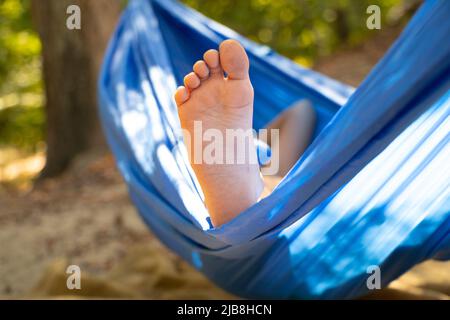 piede dei bambini in un'amaca, rotolare nella foresta in estate al sole, riposare in un'amaca, un piede in un'amaca, riposare nella foresta Foto Stock